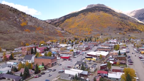 Drone-flying-over-Silverton-Colorado,-former-mining-town,-with-the-Rocky-Mountains-in-the-background-during-the-fall-in-the-late-afternoon