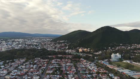 Drone-panoramic-view-of-Salta,-Argentina,-houses-mountains-dramatic-clouds