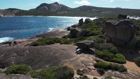 Couple-sitting-on-table-between-rocks-of-coastline-in-Australia