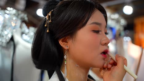 Chinese-woman-putting-on-makeup-for-photo-shoot-in-Han-style-clothing,-close-up