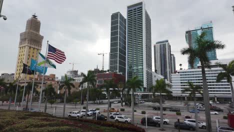 Downtown-Miami-skyline-with-skyscrapers-and-American-flags-under-a-cloudy-sky