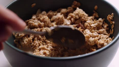 Close-Up-Bowl-of-Almond-and-Raisin-Granola-Being-Stirred-and-Picked-Up