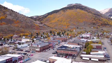 Drone-flying-backward-over-Silverton-Colorado,-former-mining-town,-with-the-Rocky-Mountains-in-the-background-during-the-fall-in-the-late-afternoon