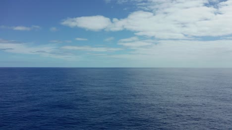 Toma-Aérea-De-Mar-Abierto-Y-Tranquilo-En-El-Pacífico-Con-Nubes-Dispersas-Y-Horizonte