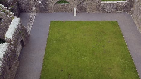 Claregalway-Friary-ruins-and-grounds-with-tombstones-and-broken-walls-without-roofs,-aerial