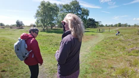 Female-walking-friends-on-rural-countryside-trail-discuss-direction