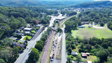 Vista-Panorámica-De-Las-Vías-Del-Tren,-Línea-De-Tren-Y-Automóviles-Circulando-Por-La-Calle-En-La-Ciudad-Principal,-Barrio-Suburbio-De-Matorrales,-Ourimbah,-Australia,-Avión-Teledirigido