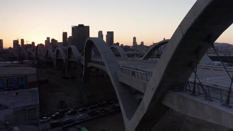 Toma-Aérea-De-Seguimiento-Bajo-A-Lo-Largo-Del-Puente-De-La-Calle-6-Y-El-Viaducto-En-El-Centro-De-Los-Ángeles,-California-Al-Atardecer.