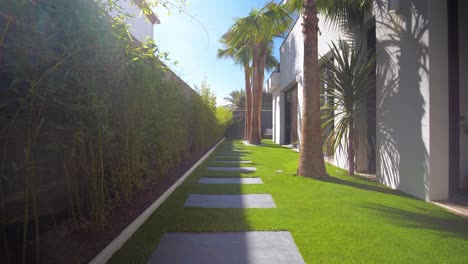 Toma-En-Primera-Persona-De-Una-Pasarela-De-Piedra-Con-Palmeras-En-El-Jardín-De-Una-Villa-Francesa