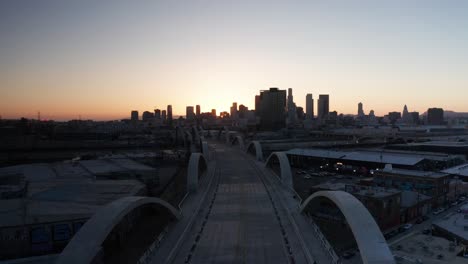 Toma-Aérea-Baja-Volando-Sobre-El-Puente-De-La-Calle-Sexta-Y-El-Viaducto-Al-Atardecer-En-El-Centro-De-Los-Ángeles,-California.