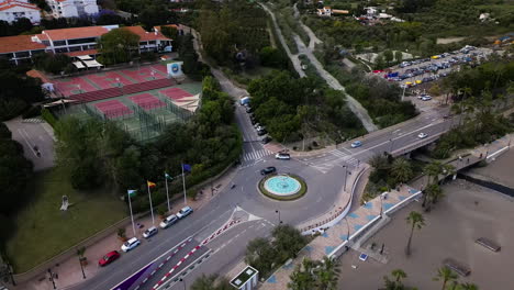 Calles-De-La-Ciudad-Con-Rotonda,-Playa-Y-Canchas-Deportivas,-Vista-Aérea