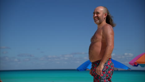 Zeitlupe-Eines-Glücklichen-Mexikanischen-Lateinamerikanischen-Mannes-Mit-Bauch-Und-Alternativem-Hipster-Haarschnitt,-Der-Beim-Sonnenbaden-Am-Strand-In-Cancun-Lächelt