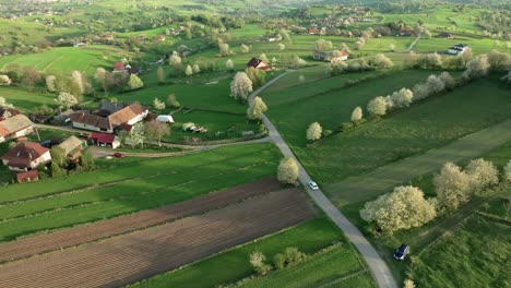 Aerial-view-of-a-picturesque-countryside-village-in-Central-Slovakia,-surrounded-by-lush-greenery-and-blooming-pear-trees-during-springtime