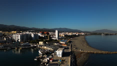 Paisaje-Urbano-Costero-De-Estepona-Con-Playa-De-Arena-Y-Montaña-En-El-Horizonte,-Vista-Aérea