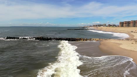 An-aerial-view-of-waves-crashing-against-the-beach-in-Far-Rockaway,-Queens