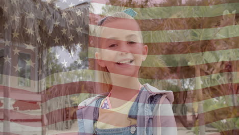 Animation-of-american-flag-over-porttrait-of-smiling-caucasian-girl-in-sunny-garden