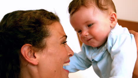 Mother-cuddling-her-baby-boy-on-bed