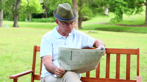 Hombre-Jubilado-Leyendo-El-Periódico-En-Un-Banco-Del-Parque