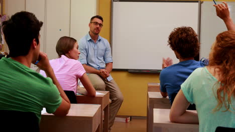 Lecturer-sitting-and-speaking-to-his-students-in-classroom