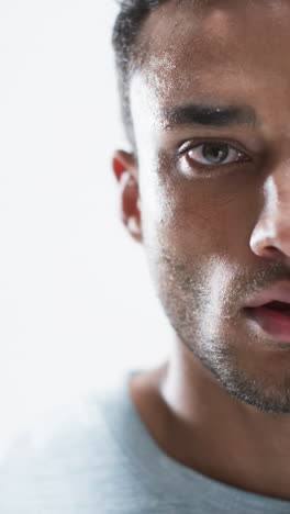 Vertical-video:-Biracial-male-athlete-showing-focus,-white-background