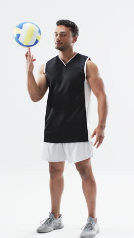 Vertical-video:-Biracial-male-athlete-balancing-volleyball,-white-background