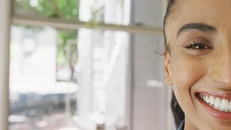 Retrato-De-Media-Cara-De-Una-Feliz-Barista-Birracial-Sonriendo-En-Una-Cafetería,-Espacio-Para-Copiar