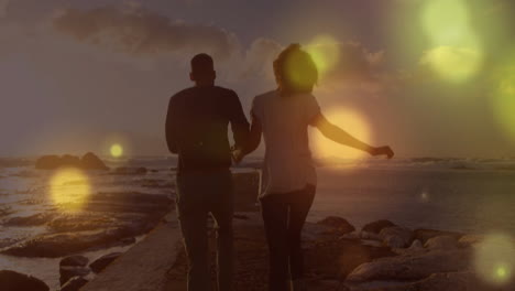 Animation-of-light-spots-over-biracial-couple-running-at-beach