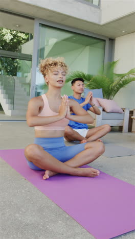 Vertical-video:-Diverse-couple-practicing-yoga-on-purple-mats