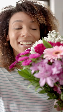 Video-Vertical-De-Una-Mujer-Birracial-Feliz-Con-Flores-Teniendo-Videollamada-Del-Día-De-San-Valentín,-Cámara-Lenta