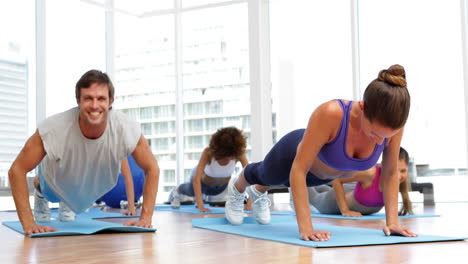 Fitness-class-doing-push-ups-together-on-exercise-mats