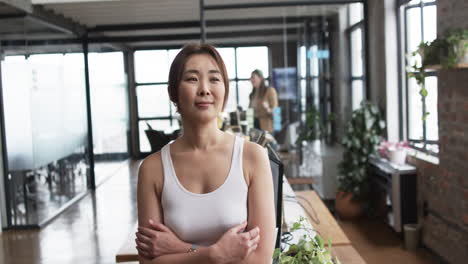 Asian-elder-woman-professional,-arms-crossed,-with-team-behind