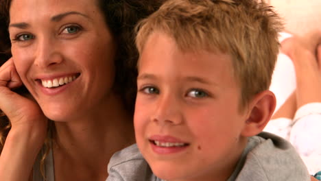 Mother-and-son-lying-on-bed-smiling-at-camera
