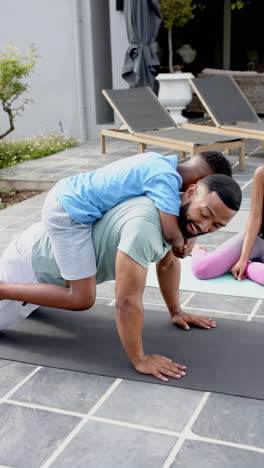 Vertical-video:-Family-enjoying-outdoor-fun-outdoors,-son-climbing-on-father''s-back