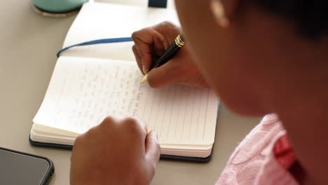 Mujer-Afroamericana-Está-Escribiendo-En-Un-Cuaderno,-Fondo-Gris