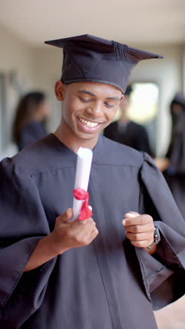 Vertical-video:-In-highschool,-young-biracial-male-student-is-graduating