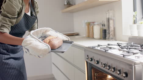 A-young-African-American-woman-wearing-oven-mitts-holding-freshly-baked-bread