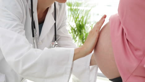 Doctor-talking-to-her-pregnant-patient-and-examining-her-bump