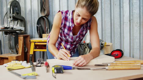 Focused-carpenter-marking-a-wooden-plank-with-pencil