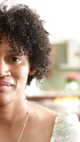 Vertical-video:-Biracial-woman-with-curly-hair,-wearing-necklace,-smiling