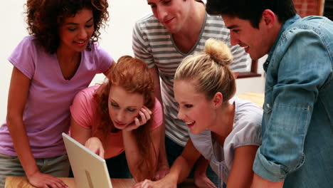 Cheerful-young-students-using-laptop-together