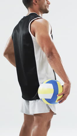 Vertical-video:-Biracial-male-athlete-holding-volleyball,-white-background