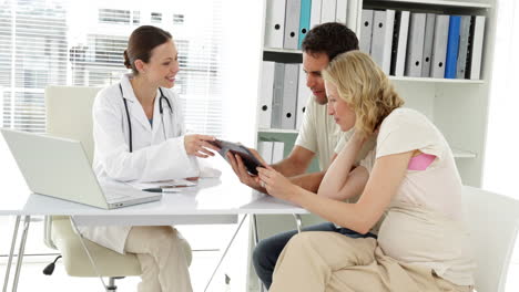 Doctor-talking-with-expectant-parents-showing-them-tablet-screen