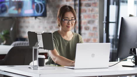 Asian-senior-professional-working-with-laptop-and-tablet-at-desk