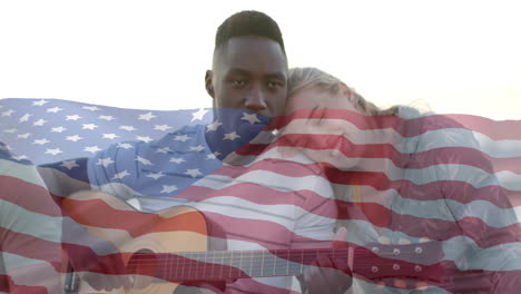 Animation-of-flag-of-usa-over-diverse-friends-playing-guitar-on-beach