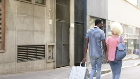 A-diverse-couple-strolls-hand-in-hand-down-city-street,-copy-space