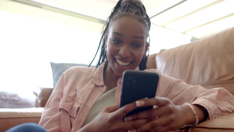 African-American-young-woman-holding-smartphone,-wearing-pink-shirt