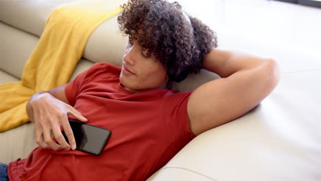 Un-Joven-Birracial-Se-Relaja-Con-Auriculares-En-El-Sofá-De-Casa