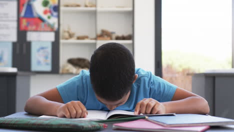 En-La-Escuela,-En-Un-Aula,-Un-Joven-Estudiante-Birracial-Se-Concentra-En-La-Lectura