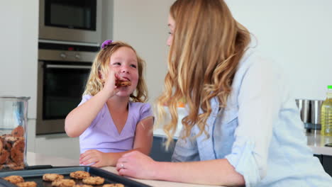 Little-girl-having-milk-and-cookies-with-her-mother