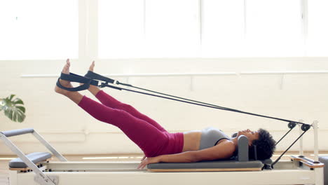 Biracial-woman-exercising-on-Pilates-reformer